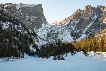 A view of Dream Lake in Rocky Mountain National Park with snow covered peaks surrounded by a forest of trees, snow, and ice.
