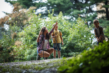 Fototapeta premium Mother and her little sons hiking trough forest .They learning about animal and plant life. 