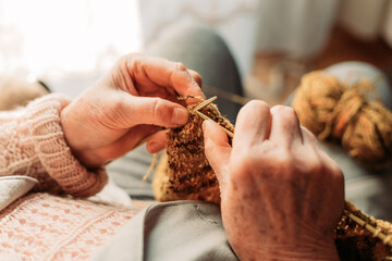 Close-up of elderly woman hands knitting. Wintertime