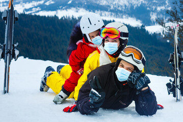 Fototapeta na wymiar family wearing a medical mask during COVID-19 coronavirus on a snowy mountain at a ski resort