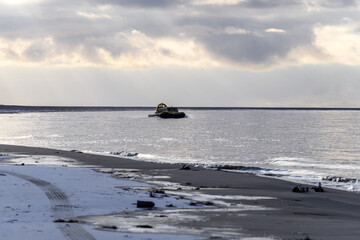 Hovercraft flying above water. Air cushion sailing near beach. Yellow hover craft under way.