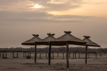 Reed and wood beach umbrellas on the beach - Sulina, Romania