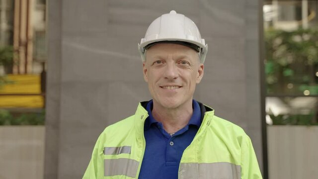 Face portrait of Caucasian engineer manager man looking at camera with confident smile and Crossed arms and believe of company service quality at outdoor

