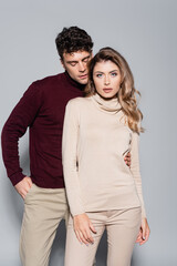  young couple in turtleneck jumpers posing isolated on grey