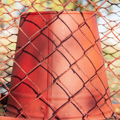 Red fire bucket behind a chain link net