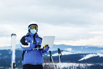 medical mask as protection against coronavirus. guy in the mountains isolated from coronavirus. works on laptop