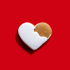 Festive biscuit. Valentine Day. Holiday bakery food. Beige homemade gingerbread heart cookie with white icing decoration isolated on bright red background.