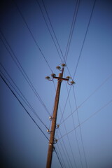 old wooden pillar with wires blue sky background.