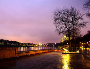 Evening city, embankment, winter, trees without leaves.