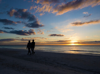 Silhouette of a couple walking on the beach at sunset on the Gulf of Mexico at St. Pete Beach, Florida.