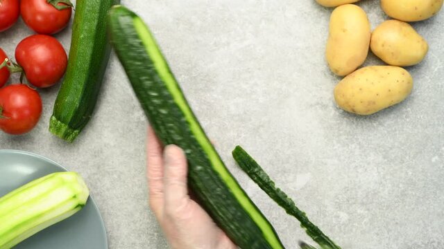 Woman peeling fresh cucumber,  preparing vegetable salad