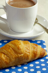 tasse de chocolat chaud et viennoiserie sur une table