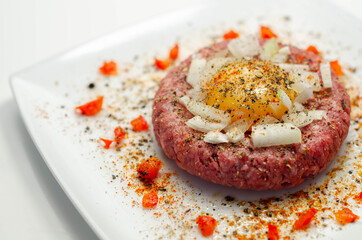 Beef steak tartare with raw egg yolk and onion with tomato