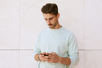 Young handsome bearded hipster man using his smartphone. Outdoor portrait.