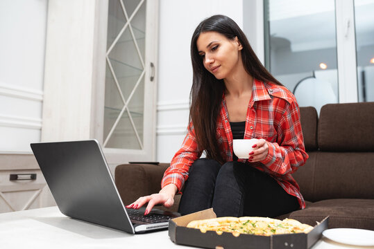 smiling girl working from home on laptop sitting on sofa