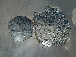 Top drone view of couple of heaps of broken glass bottles. Garbage on asphalt. Waste sorting. Environmental pollution.