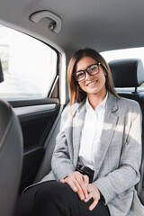 happy, businesswoman smiling at camera while riding in car on blurred foreground