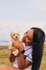 Young woman holding an adorable french poodle mini puppy