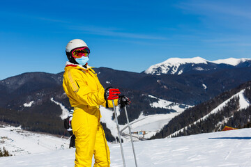 Fototapeta na wymiar Woman wearing a medical mask during COVID-19 coronavirus on a sunny winter day at a ski resort