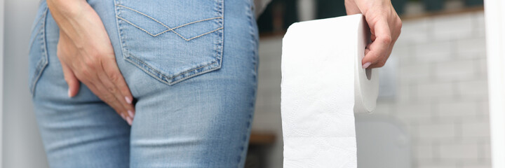 Woman holds hand on priest in other hand toilet paper and stands opposite the humiliated. Constipation and bloating concept
