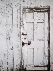 The  old white wooden door could use a fresh coat of paint.