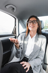 Fototapeta na wymiar businesswoman in eyeglasses pointing with hand while riding in car