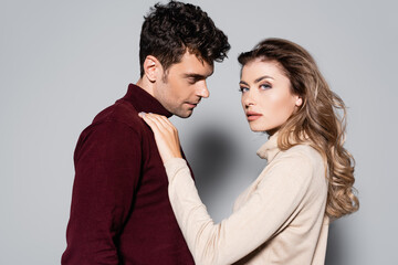 side view of young couple in turtleneck jumpers isolated on grey