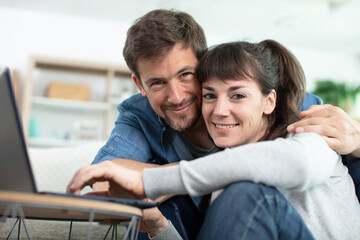 young couple relaxing on sofa with laptop