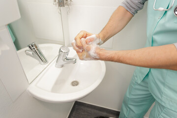 male doctor washing hands with soap