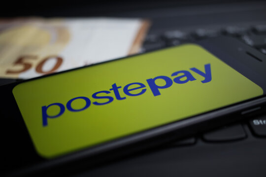 Viersen, Germany - April 9. 2020: Close up of mobile phone screen with logo lettering of Postepay payment provider on computer keyboard, blurred euro money background