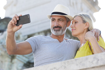 Fototapeta na wymiar senior couple with camera taking selfie on street