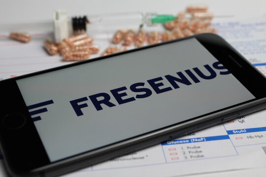 Viersen, Germany - April 9. 2020: Close up of mobile phone screen with logo lettering of Fresenius pharmaceutical company, blurred pills and lab sheet background