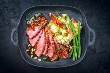 Modern style traditional gourmet duck breast filet with potato salad and beans in orange sauce offered as top view on a modern design plate