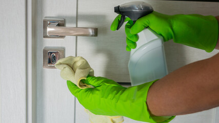 Cleaning door knob with alcohol spray for Covid-19 Coronavirus prevention