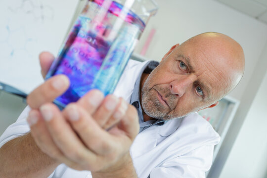 senior scientist observing a reaction in a glass flask