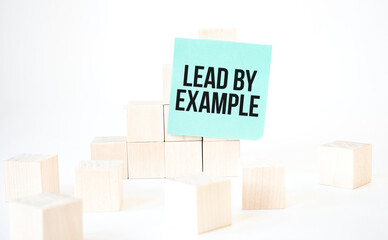 Text Lead by example writing in green card cube ladder. White background. Business concept