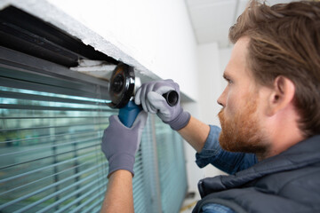 young man as a home improvement while grinding window frame