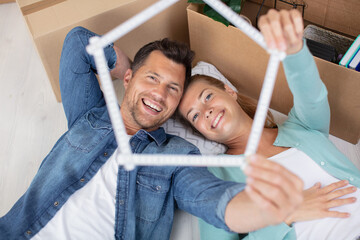 young couple moving in new home lye on floor