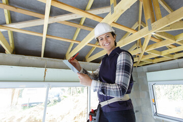 Fototapeta na wymiar female builder using screwdriver on wooden beam