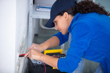 young brunette woman repairs an electric socket