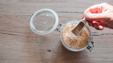 bath salt in glass with male hand on wooden table