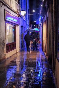 people on a rainy street with lights in Venice