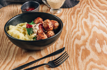 Swedish meatballs with mashed potatoes, gravy and lingonberry jam on wooden background. Selective focus