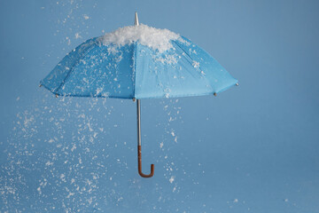 Blue umbrella on blue background with snow. Blue monday concept.