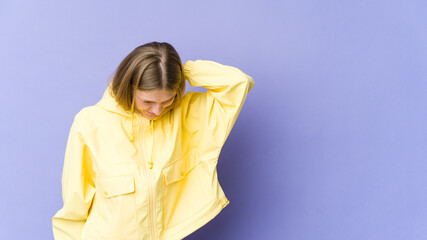 Young blonde woman isolated on purple background having a neck pain due to stress, massaging and touching it with hand.