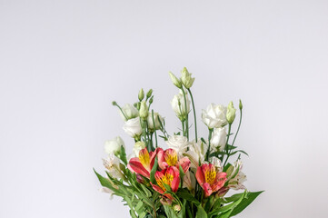 A beautiful bouquet of red and white alstroemerias and white eustomas white wall background. A bouquet for eight of March. Beautiful flowers for women's day. A bouquet as a gift. 
