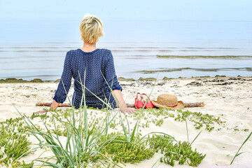 woman is sitting on the sand near the sea. Relax.