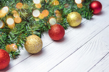 Christmas composition with fir branches, gold and red balloons on a white wooden background.