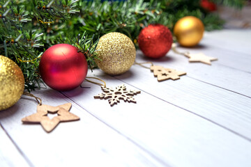 Christmas composition with fir branches, Golden and red balloons, wooden toys on a white wooden background.