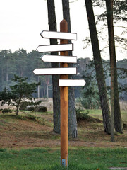 A pillar with five direction signs in a forest park. Place for inscriptions. Mock up.